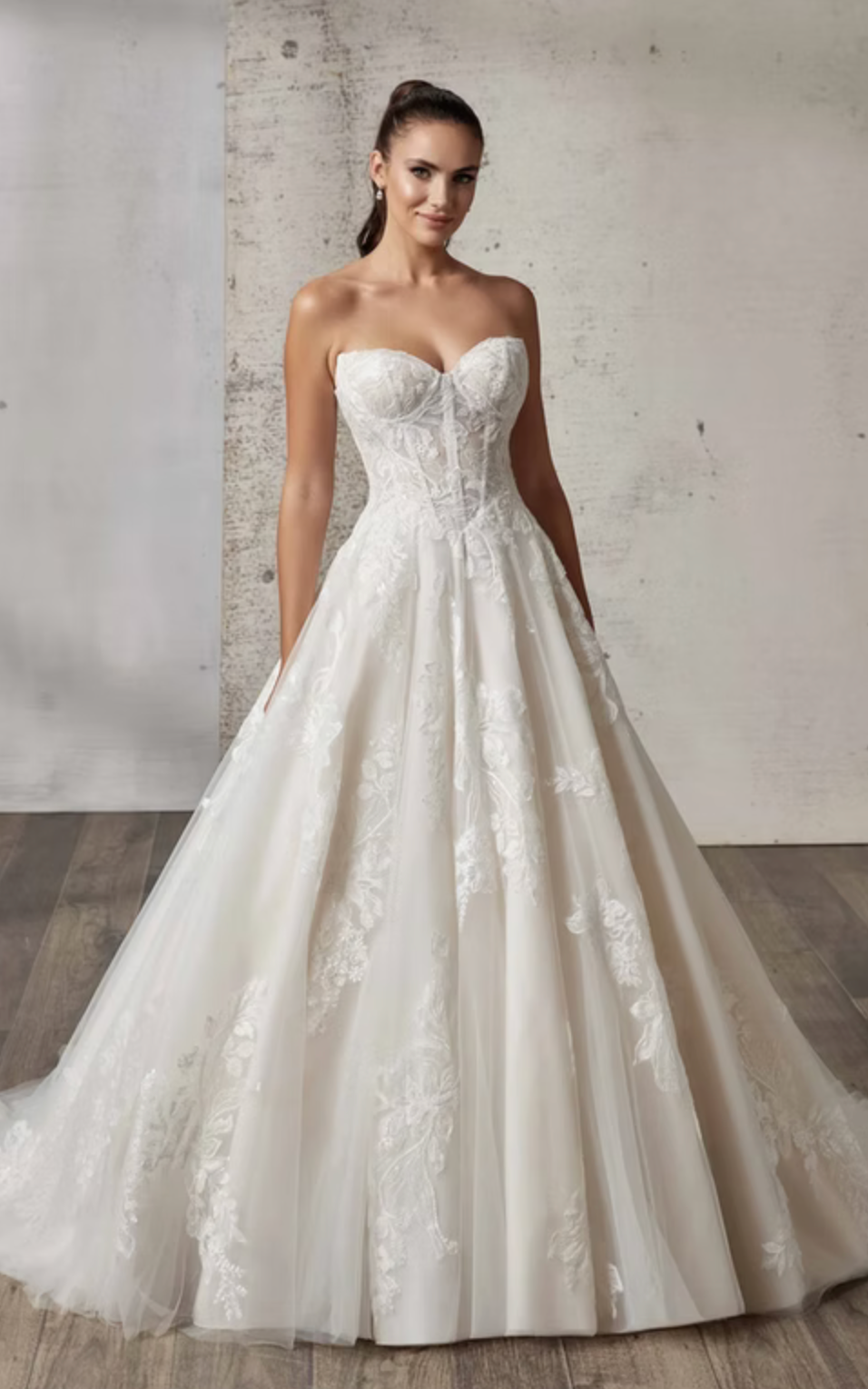 Woman wearing a white lace wedding dress against a neutral background