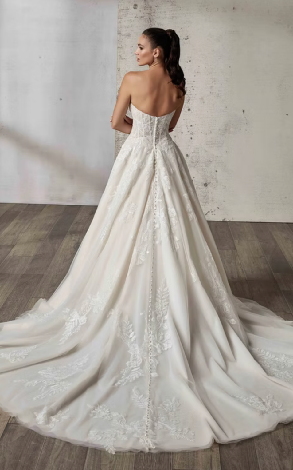 White wedding dress with lace details on a wooden floor.