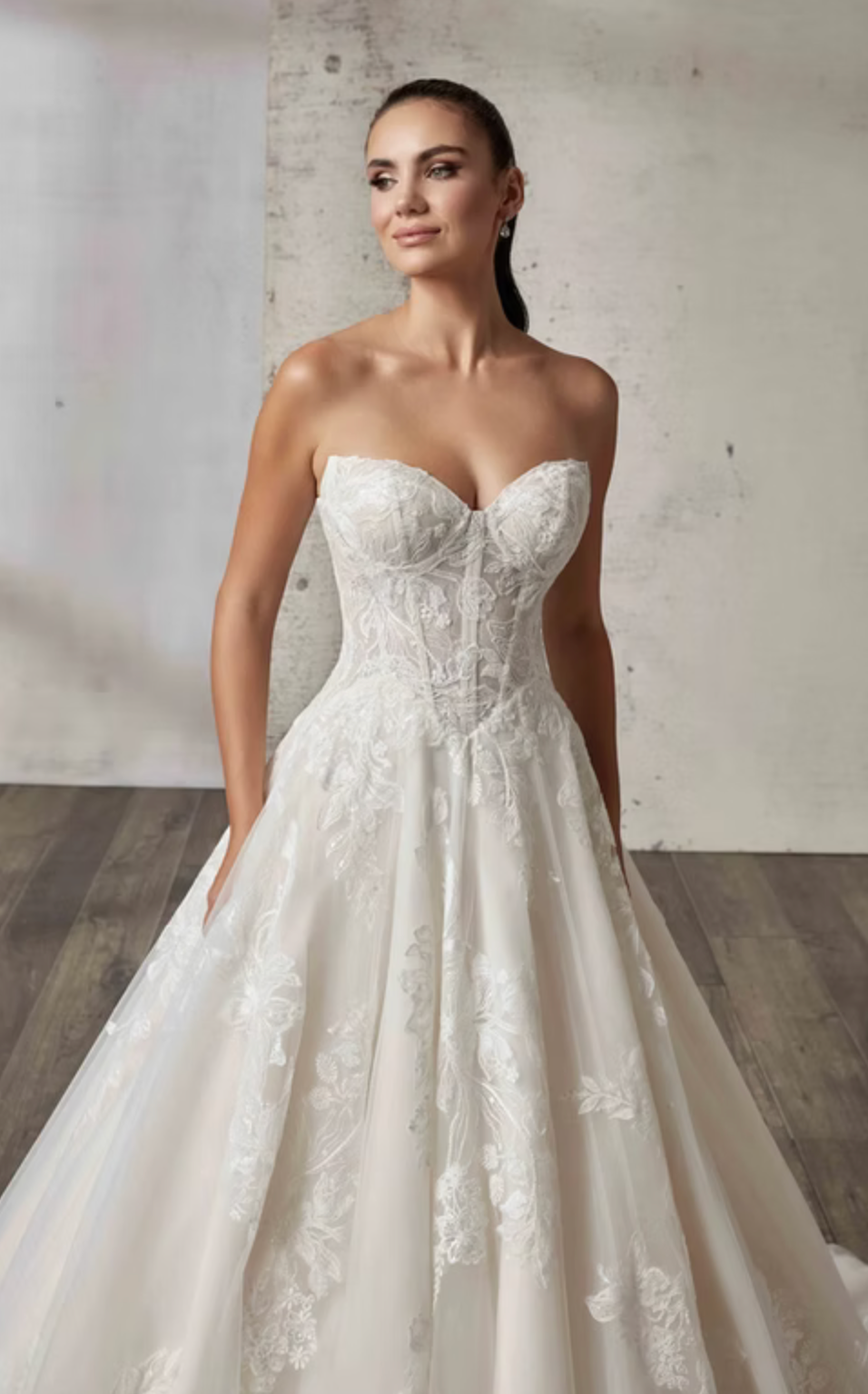 Woman wearing a strapless lace wedding dress against a plain background