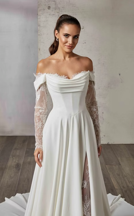 Woman wearing a white off-shoulder wedding dress with lace sleeves in a minimalistic setting.