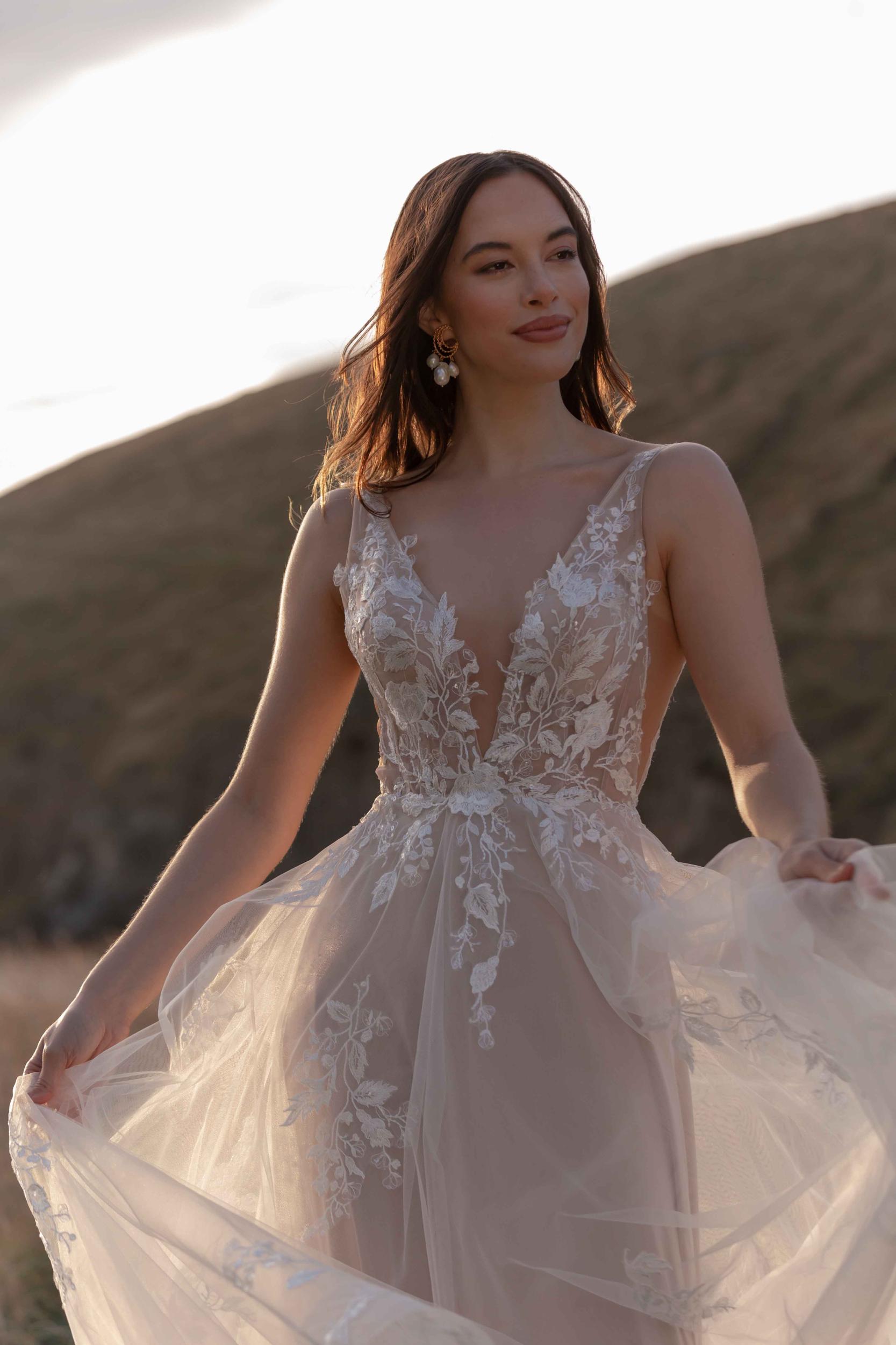 Woman in a lace wedding dress standing in a desert landscape