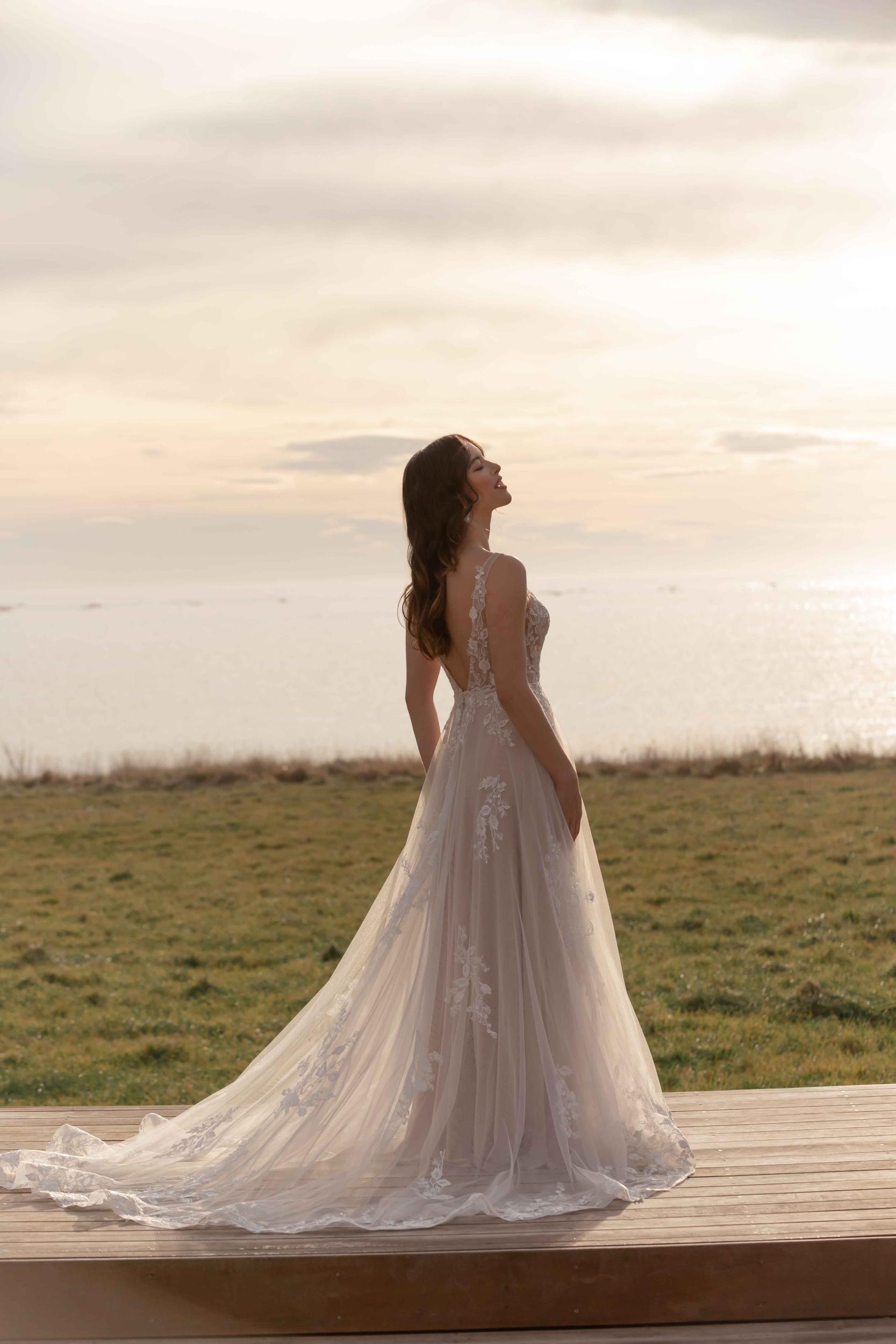 Woman in a wedding dress standing on a wooden platform with a scenic background