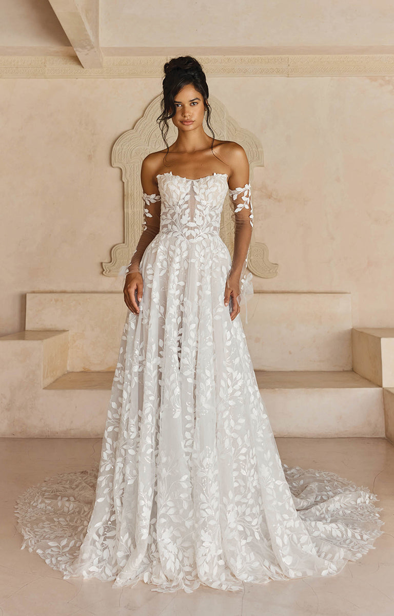 Woman wearing Laiya by Madi Lane, a white lace wedding dress in an elegant indoor setting.