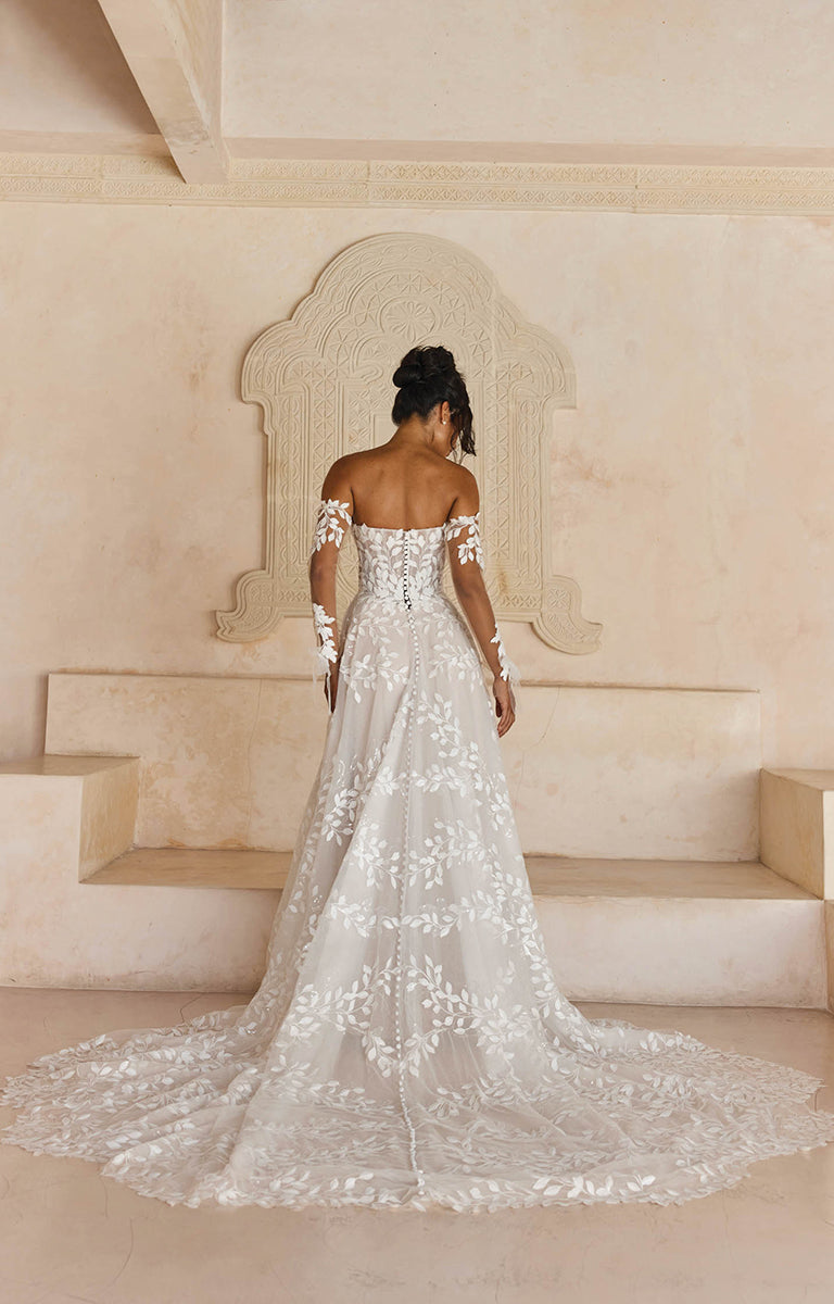 Woman in Laiya by Madi Lane, a white lace wedding dress standing in a elegant interior setting.