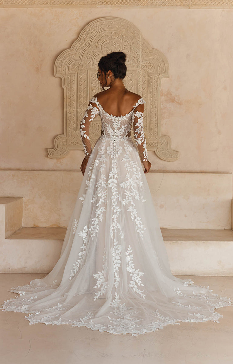 Woman wearing Landon by Madi Lane, a white lace wedding dress in an elegant setting.