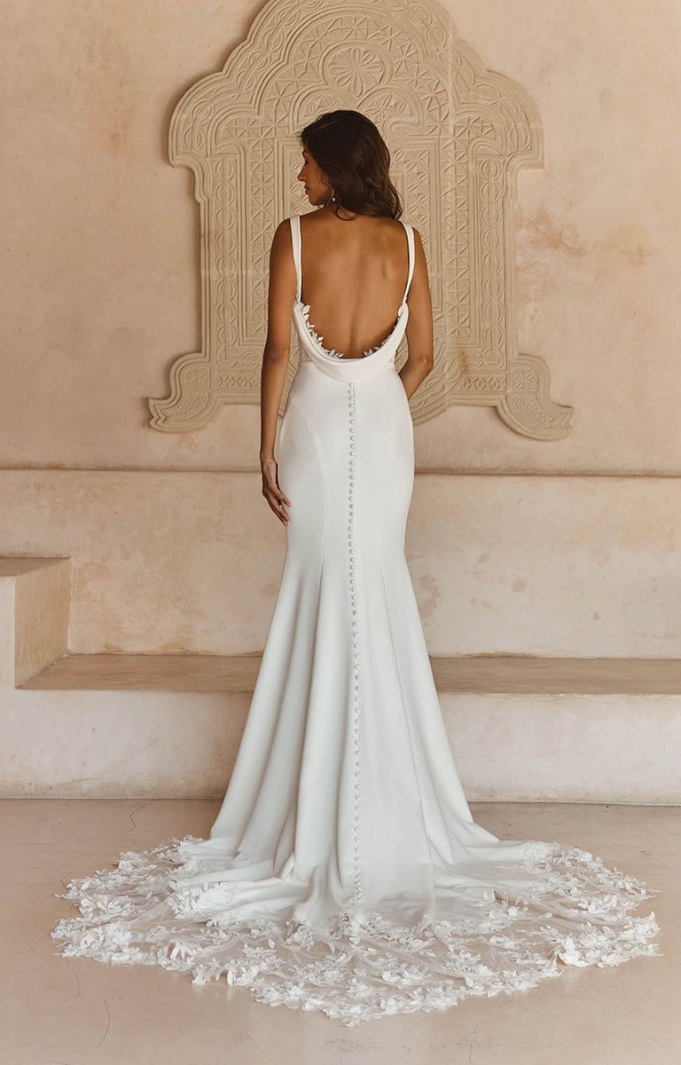 Woman in Lanette by Madi Lane, a white wedding dress standing in a room with decorative wall.