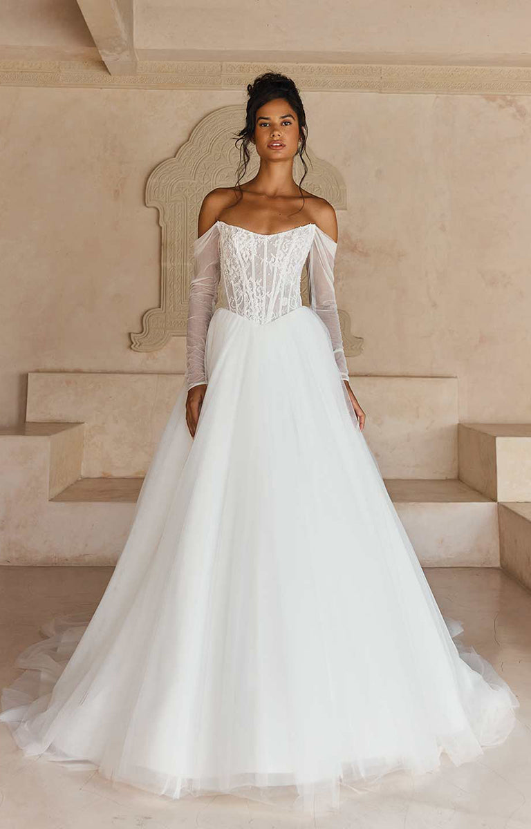 Woman in Larkin ML25140 by Madi Lane - Beaded Chantilly Lace Ball Gown with Basque Waist standing in an elegant indoor setting.