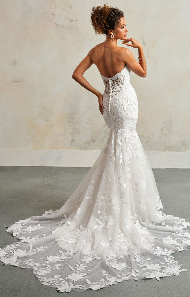 Woman wearing a white lace wedding dress with a plain background