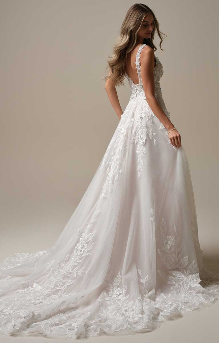 White lace wedding dress with a long train on a plain background