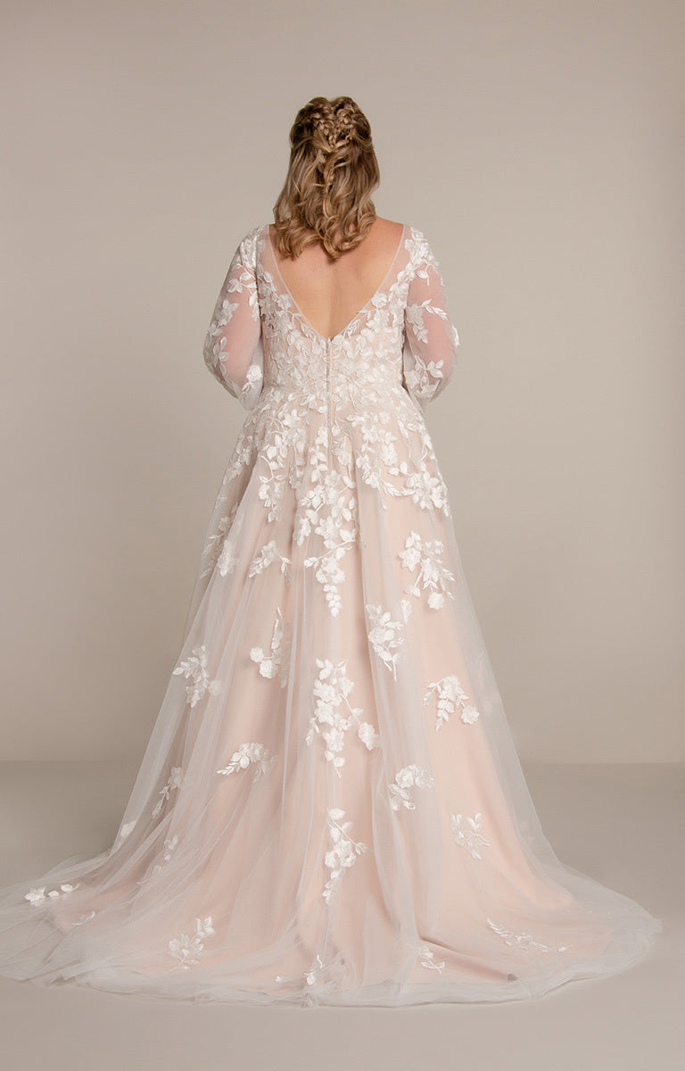 Back view of a woman wearing a floral wedding dress against a plain background