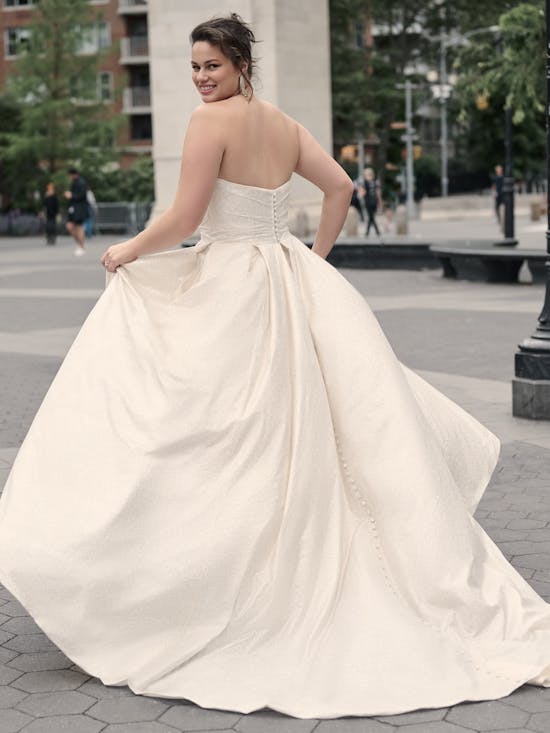 Woman in a white strapless gown standing on a city street.