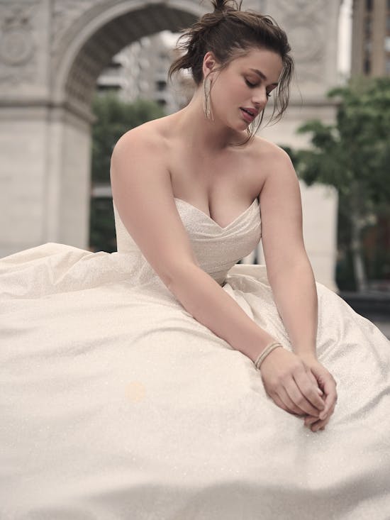 Woman in a strapless white dress sitting outdoors with a blurred background