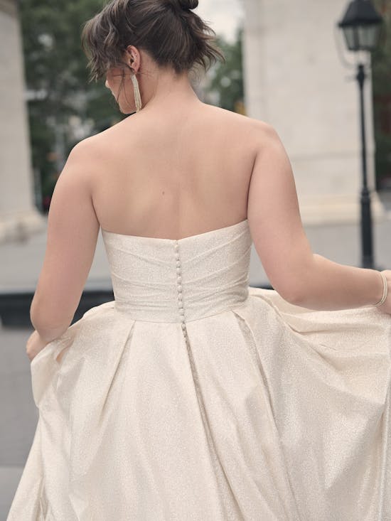 Woman wearing a strapless white gown with a blurred outdoor background