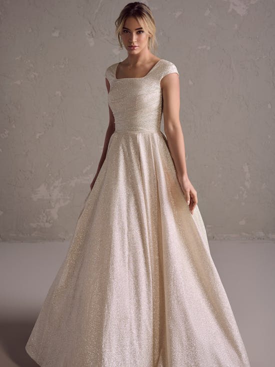 Woman wearing a beige wedding dress against a plain background
