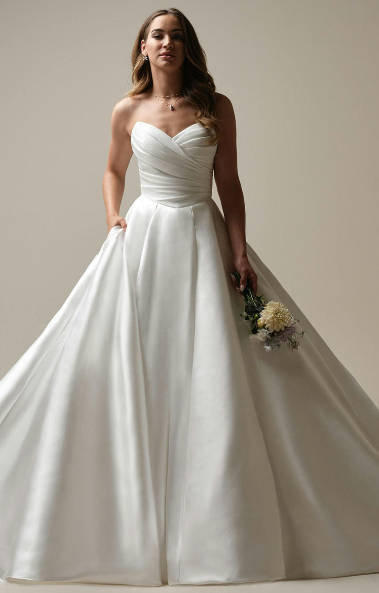 Woman wearing Aubrielle Marie by Maggie Sottero - Reena Mikado Asymmetrical Pleated Ball Gown