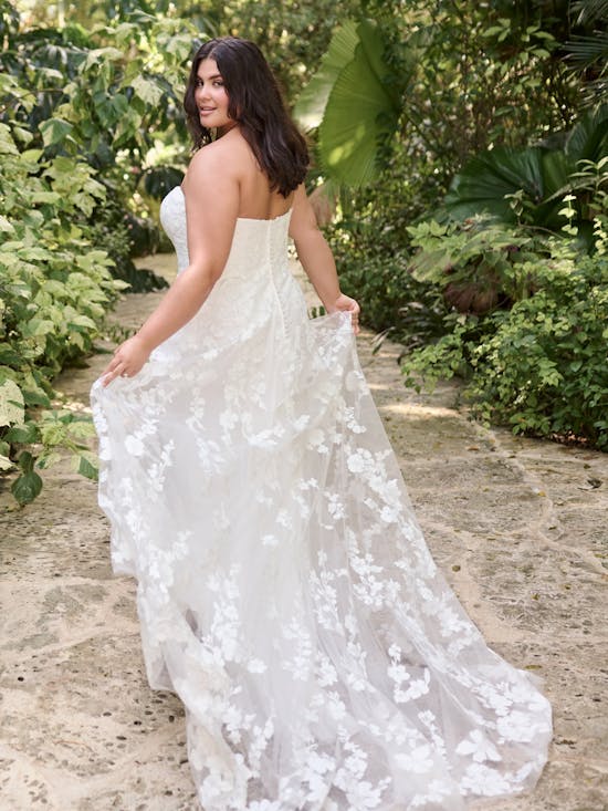 Woman in Demetria by Maggie Sottero - a white floral dress standing in a garden