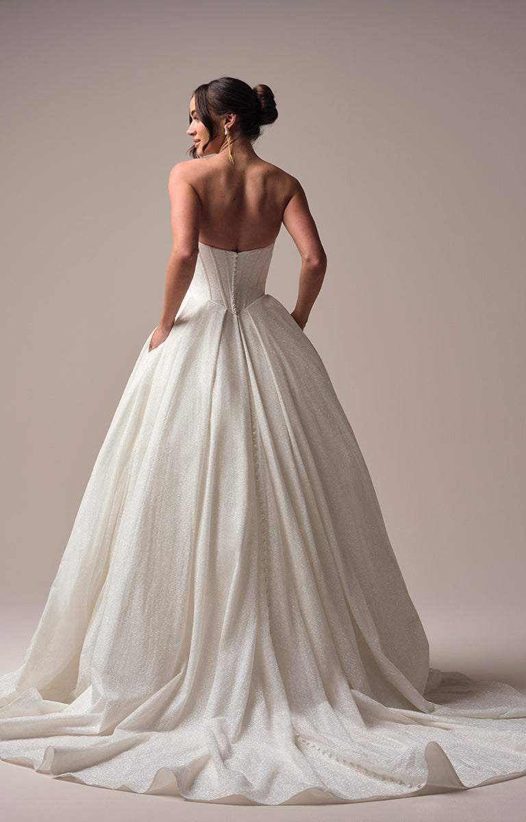 Woman wearing Derrick Royale by Maggie Sottero -  an ivory white wedding dress with a plain background