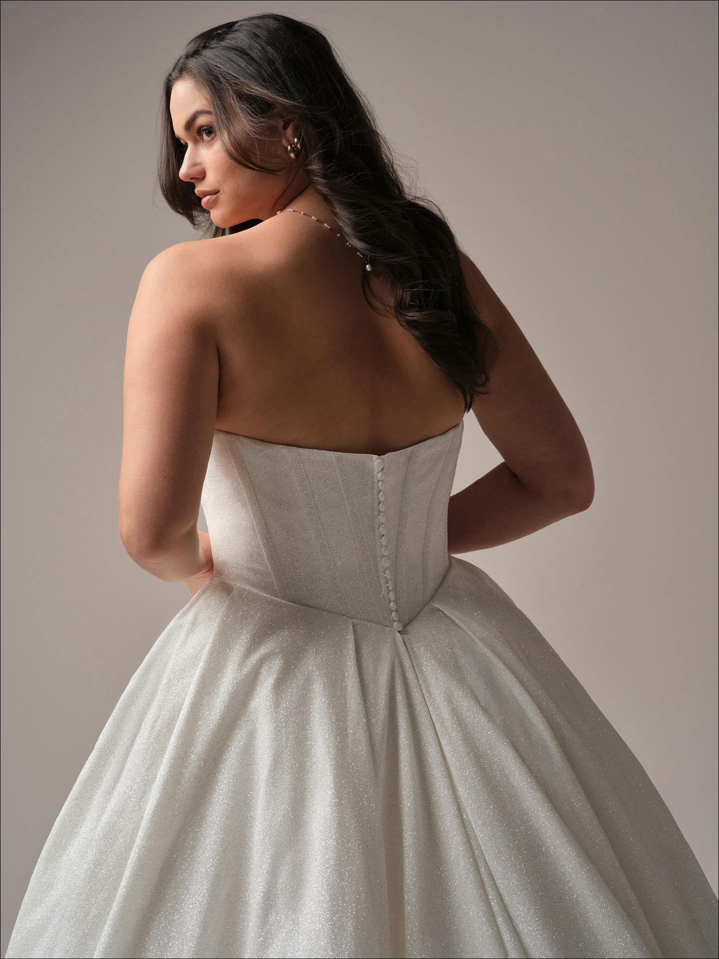 Woman wearing a strapless white wedding dress against a neutral background