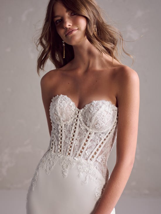 Woman wearing a strapless lace wedding dress against a neutral background