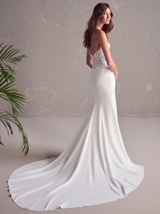 White wedding dress with a long train on a neutral background