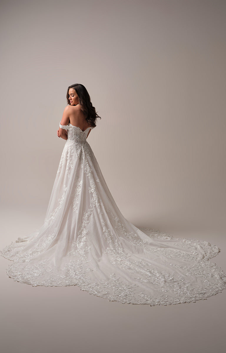 Woman wearing a white lace wedding dress against a plain background