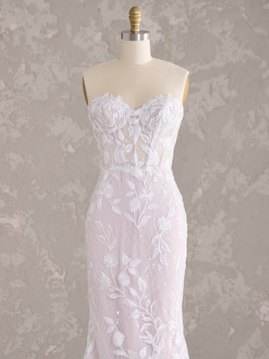 Fairchild by Maggie Sottero - White lace wedding dress on a mannequin against a textured gray background