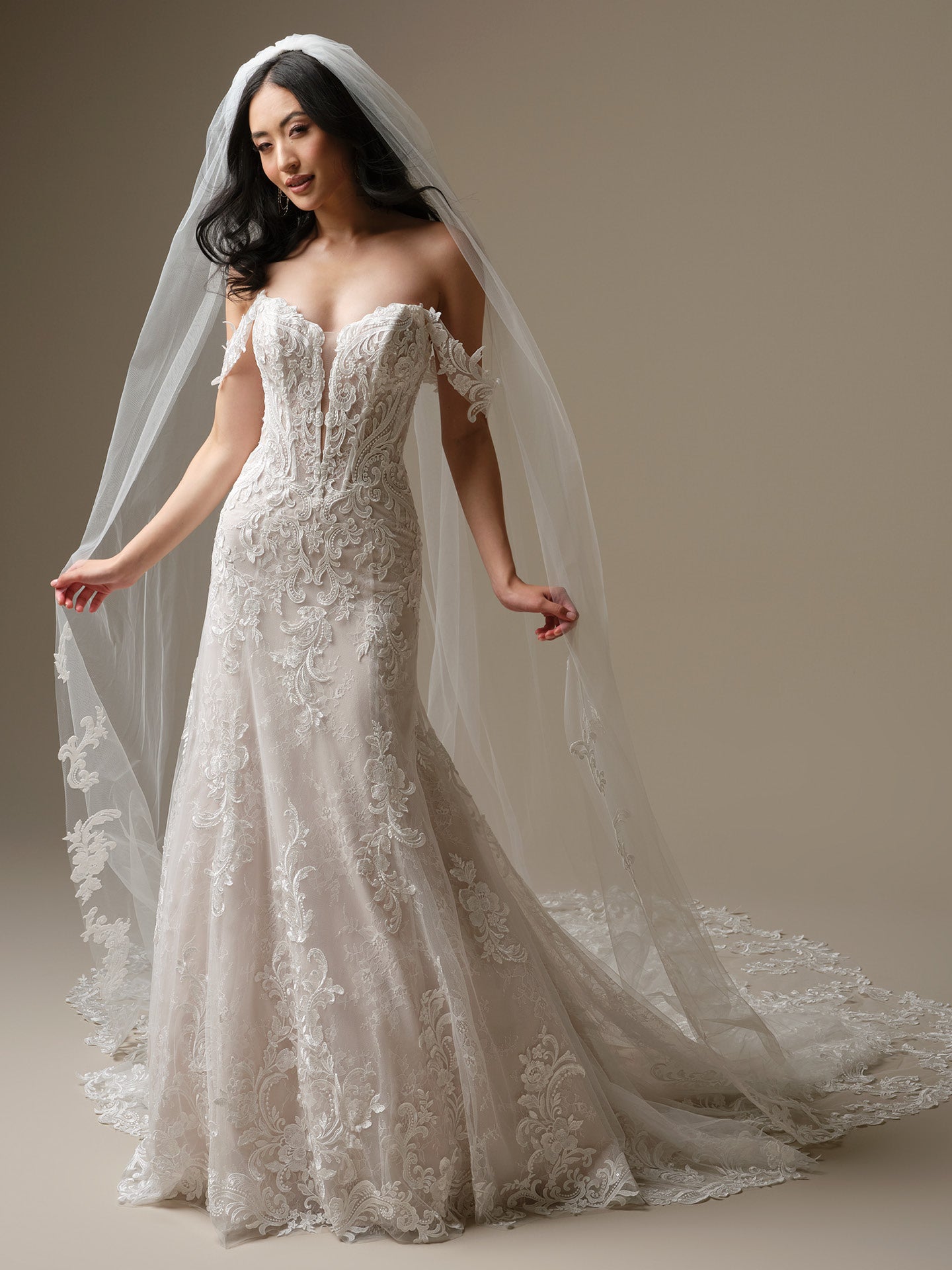 Woman wearing Farrah by Maggie Sottero - Sequin Lace A-Line Wedding Dress with Plunging Neckline with a long veil against a neutral background