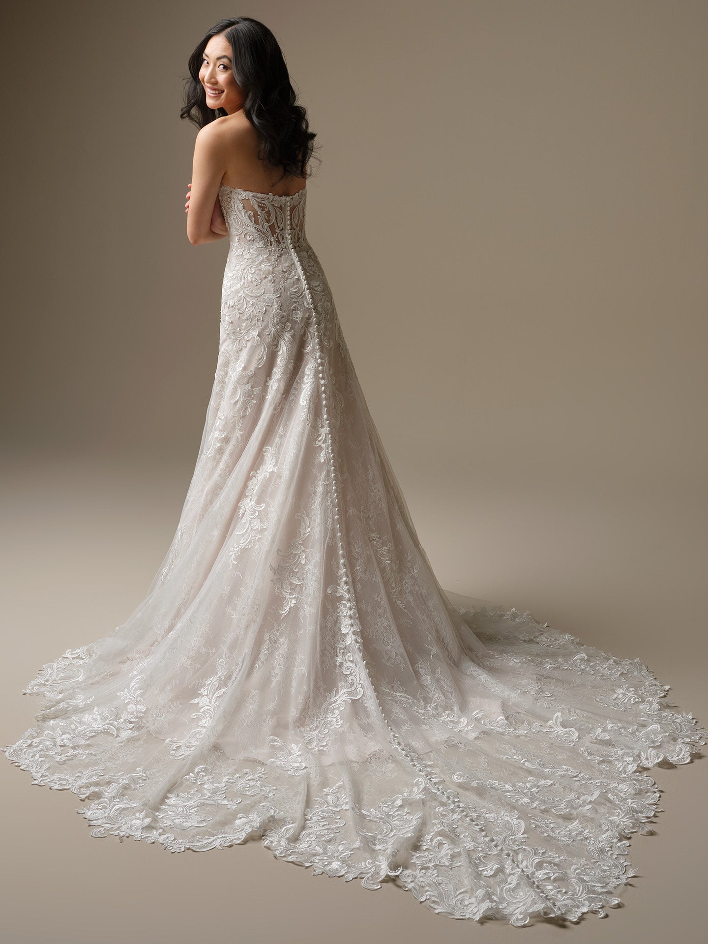 Woman wearing Farrah by Maggie Sottero - Sequin Lace A-Line Wedding Dress with Plunging Neckline against a beige background