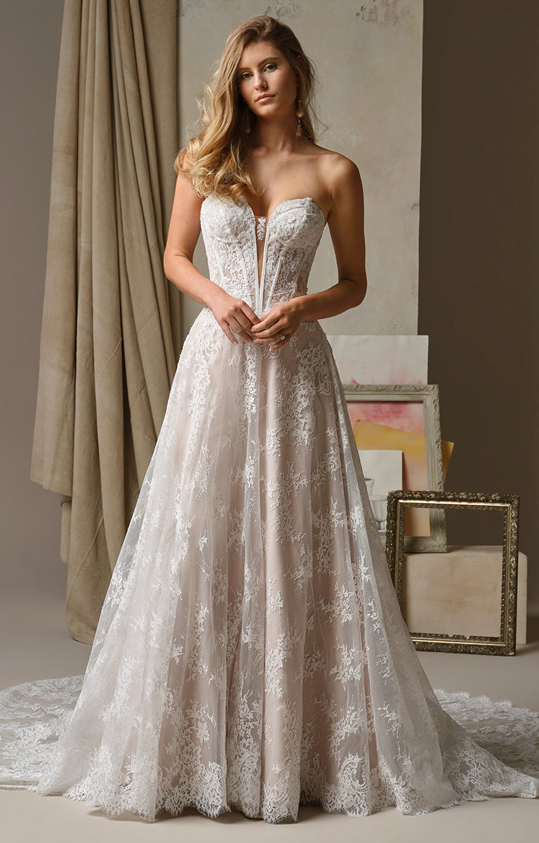 Woman wearing Lucca by Maggie Sottero - Beaded Lace Illusion Bodice A-Line Wedding Dress in a softly lit room.