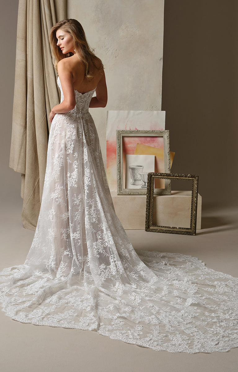 Woman in Lucca by Maggie Sottero - Beaded Lace Illusion Bodice A-Line Wedding Dress standing in a room with neutral decor.