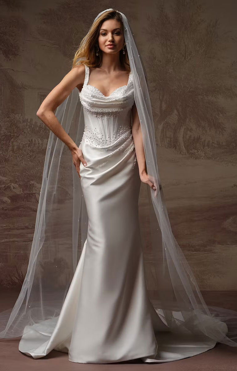 A woman modeling Melissa Marie Royale by Maggie Sottero - Pearl-Embellished Draped Satin Wedding Dress with a fitted bodice, lace-embellished sweetheart neckline, and a long sheer veil, posed against a textured brown studio backdrop.