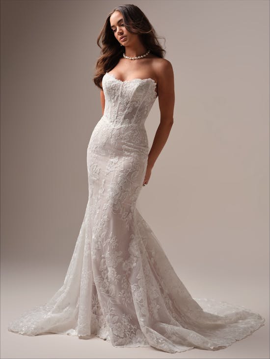 Woman wearing Meredith by Maggie Sottero - a white lace wedding dress against a plain background