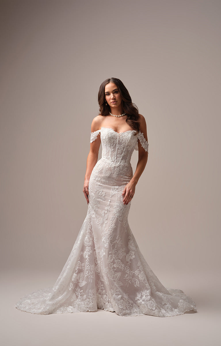 Woman wearing Meredith by Maggie Sottero - a white lace wedding dress against a neutral background