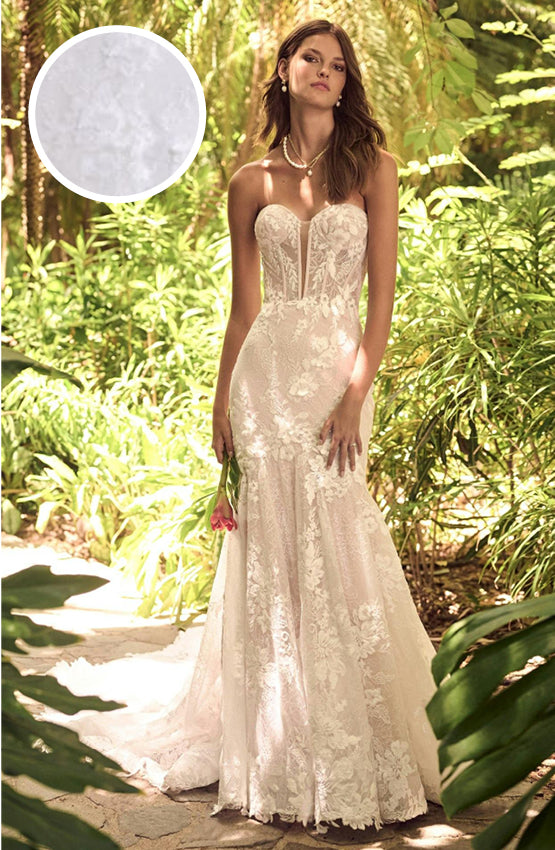Woman in Ortensia by Maggie Sottero - a white lace wedding dress standing in a lush green forest.