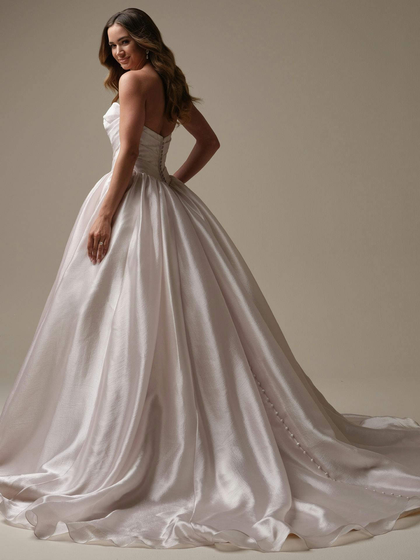 Woman wearing Paris by Maggie Sottero - a white wedding dress against a neutral background