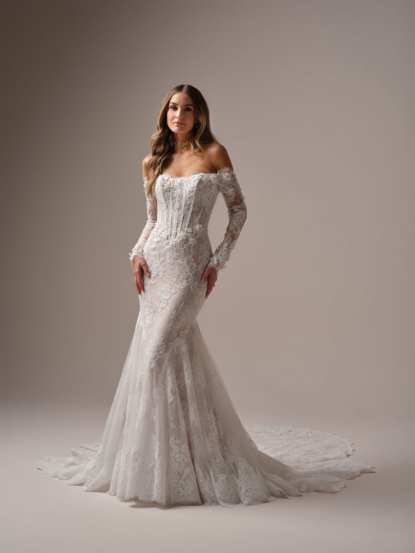 Woman wearing Takera by Maggie Sottero - 3D Floral Lace Mermaid Wedding Dress with Illusion Detailing against a plain background
