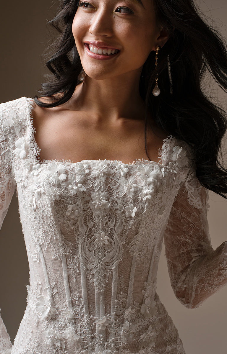 Woman wearing Takera Leigh by Maggie Sottero - Modest Fit-and-Flare Lace Wedding Dress with Illusion Sleeves with a neutral background