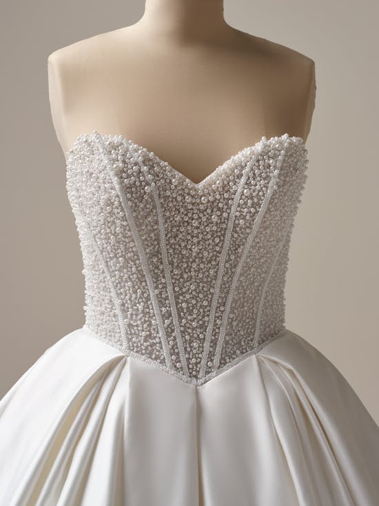White wedding dress with beaded bodice on a mannequin against a neutral background