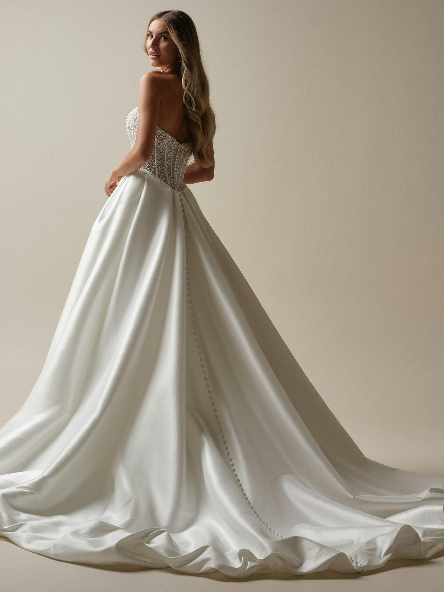 White wedding dress with intricate back design on a plain background