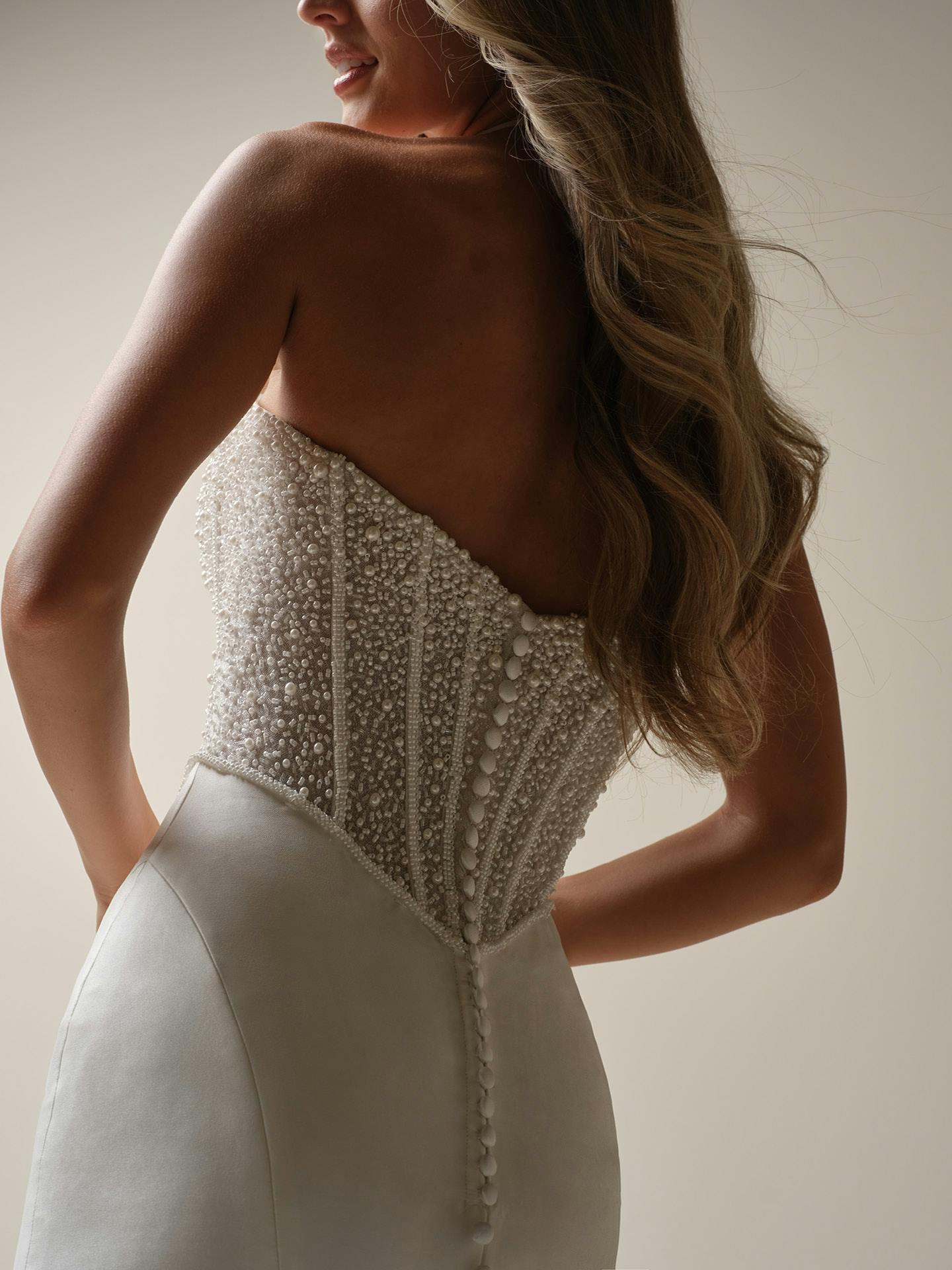 Woman wearing a beaded wedding dress with a plain background