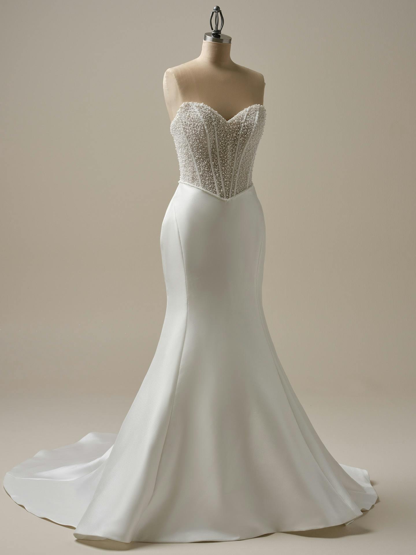 White strapless gown with beaded top on a mannequin against a beige background