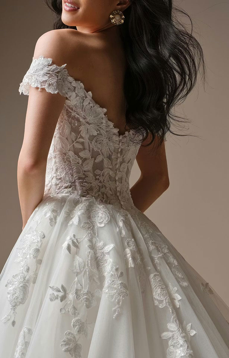Back of a woman wearing Verina Wedding Dress by Maggie Sottero - Off-the-Shoulder Lace A-Line Wedding Gown with floral lace appliqué details against a neutral background