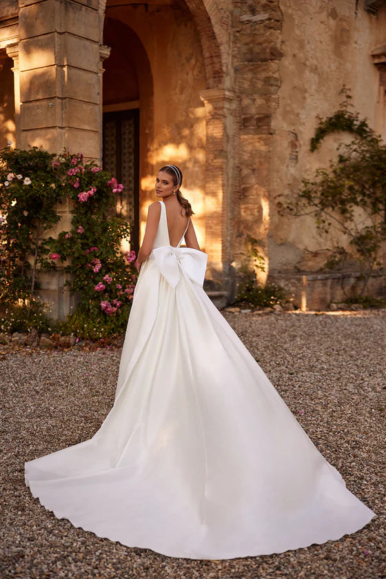 Woman in a white wedding dress standing in front of an elegant building with floral decorations.