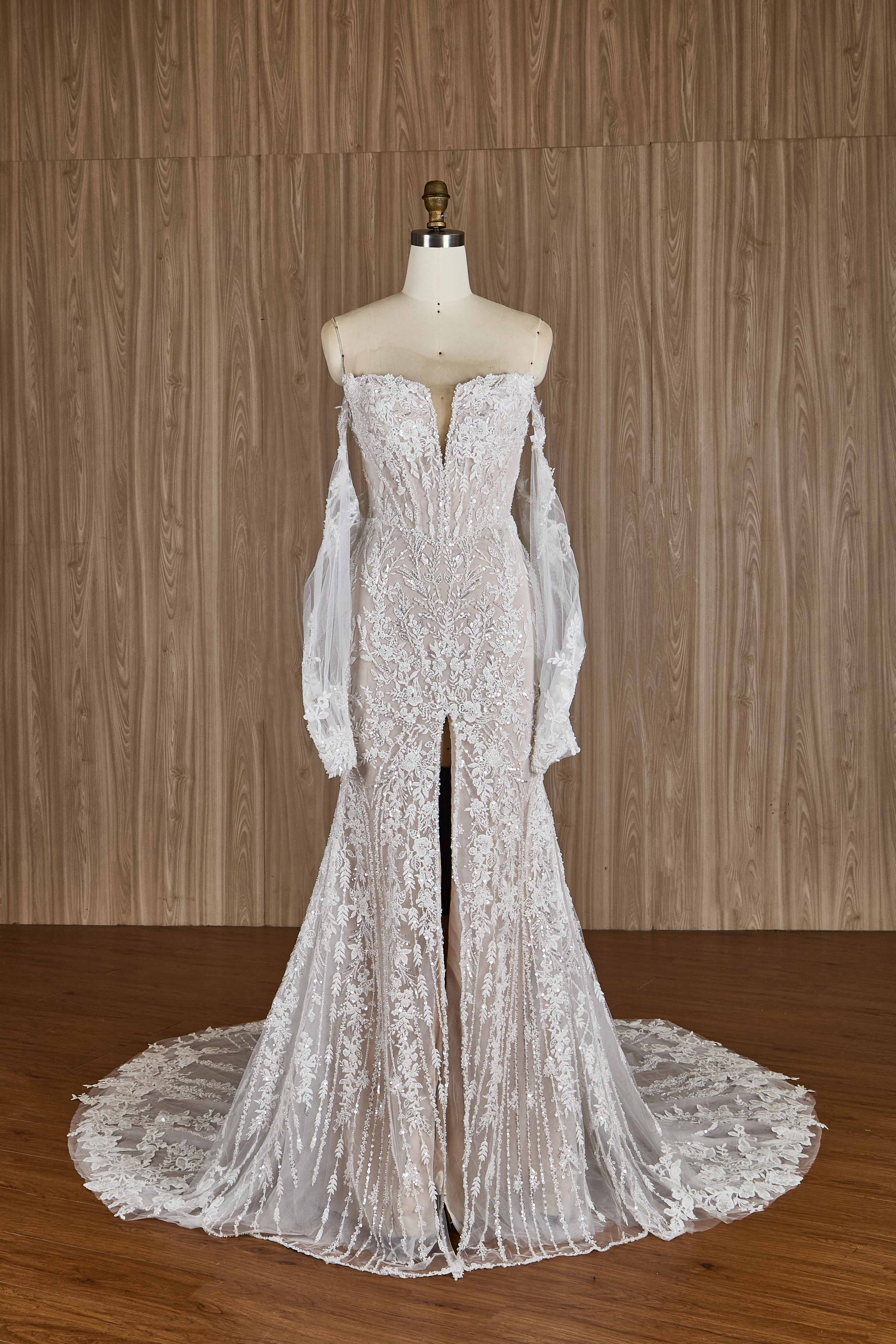 Elegant lace wedding dress on a mannequin against a wooden background