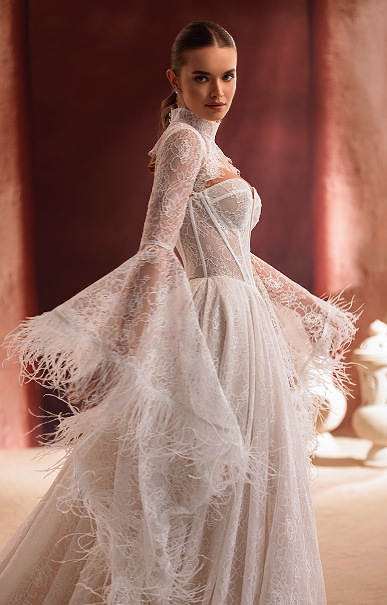 Woman wearing a white lace dress with feather details in an elegant setting.