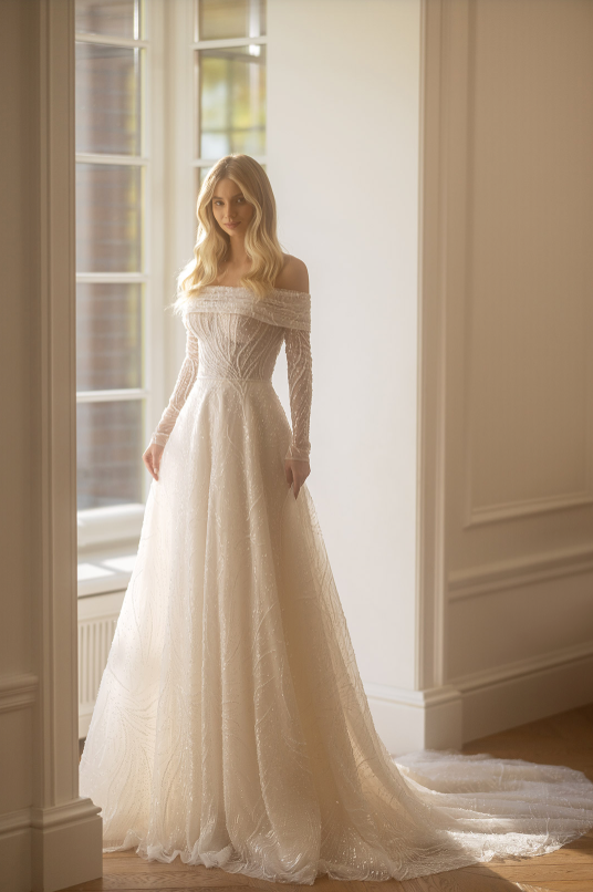Woman in a white wedding dress standing in a room with large windows.