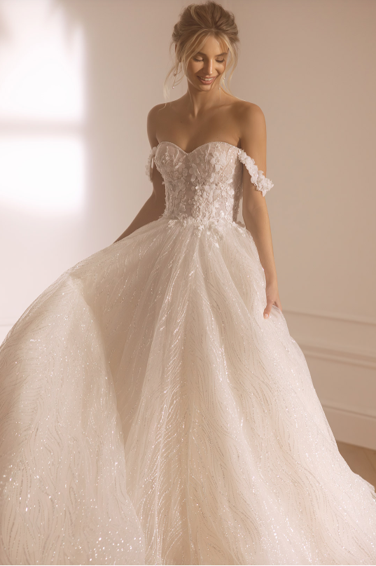 Woman wearing a white lace wedding dress indoors with soft lighting.