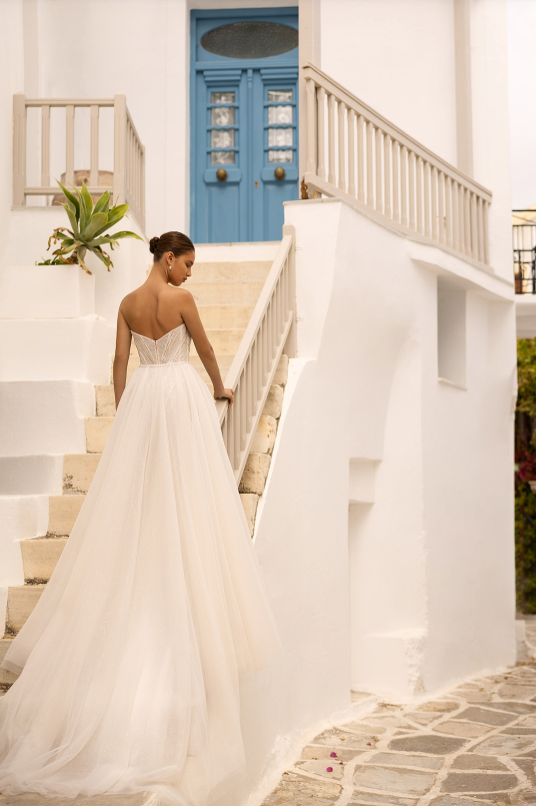 Woman in a white wedding dress standing on a staircase with a blue door in the background