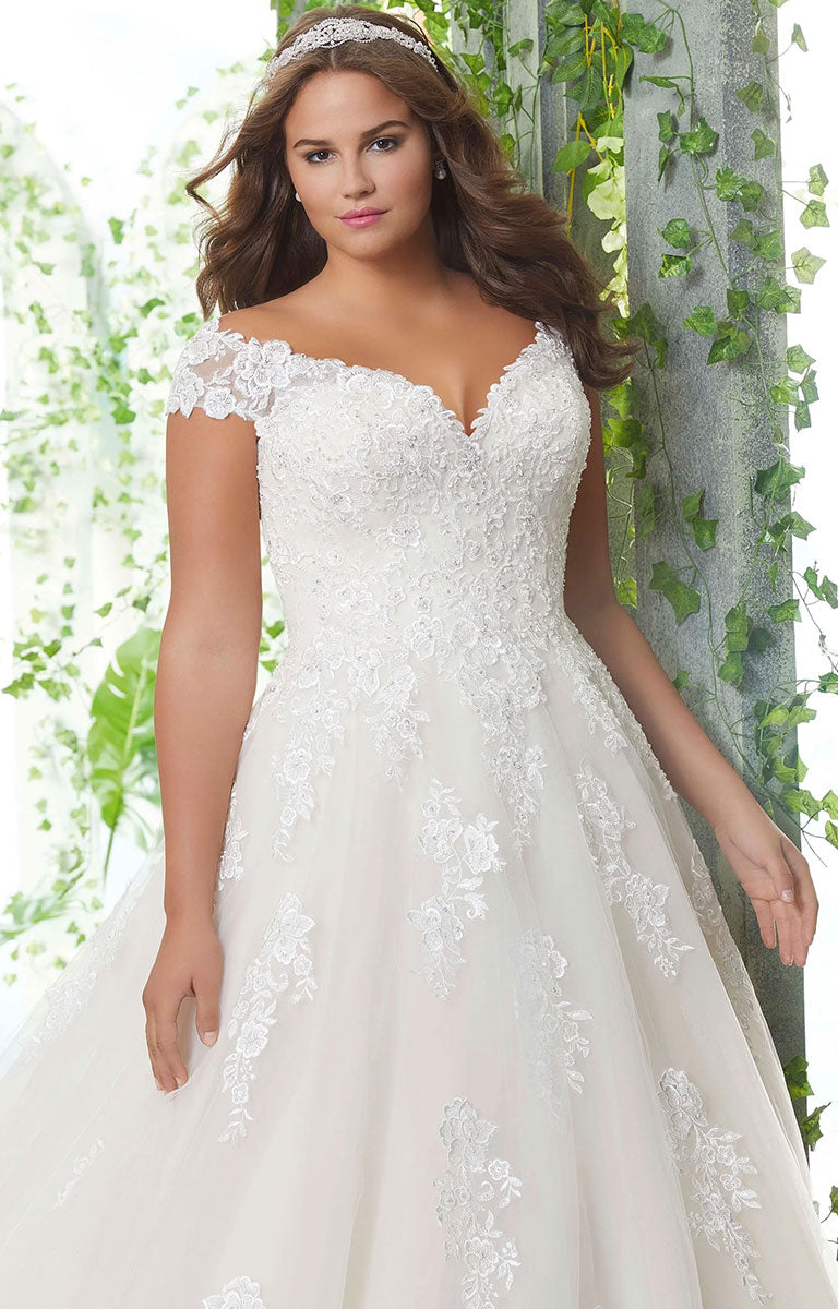 Woman wearing  Pamela Wedding Dress by Morilee Julietta - Plus Size Classic Ball Gown with Pearl and Crystal Beaded Lace Appliqués with a greenery background