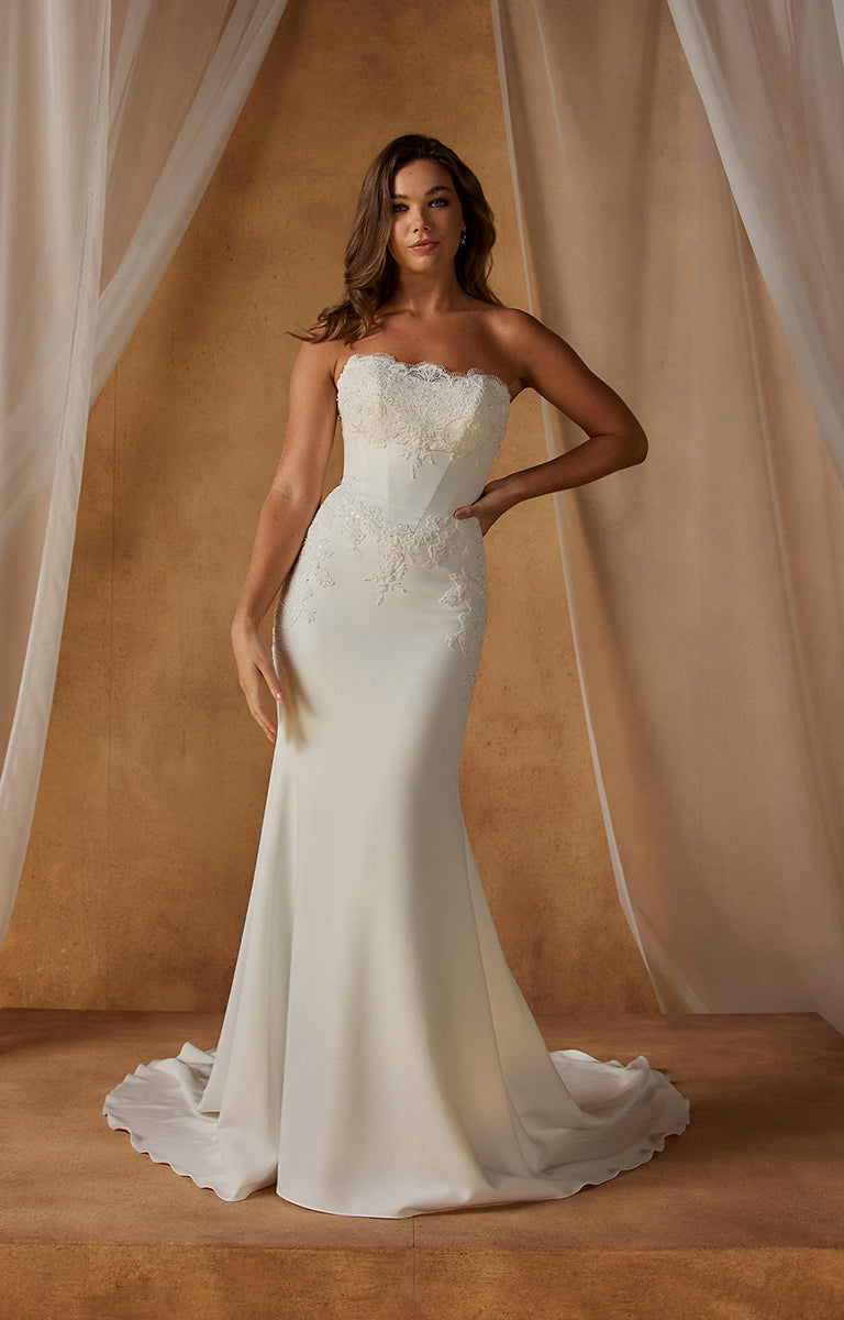 Woman wearing Natine ML26199 by Madi Lane - Fit-and-Flare Crepe Wedding Dress with Chantilly Lace Bodice against a beige curtain backdrop